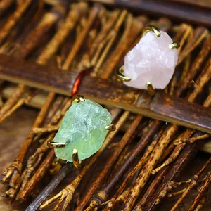 Macro detail of natural raw green fluorite and rose quartz crystal rings with gold claw setting