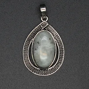 Close-up of a vintage silver teardrop pendant featuring an oval white crystal stone.