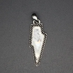 Macro detail of a vintage lightning bolt pendant featuring a natural white crystal stone.