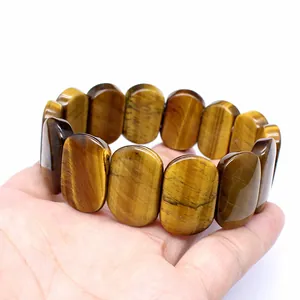 Detail of polished oval tiger's eye natural stone bracelet beads held in hand