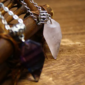 Detailed view showing the texture of natural rose quartz and fluorite crystal wolf tooth pendants