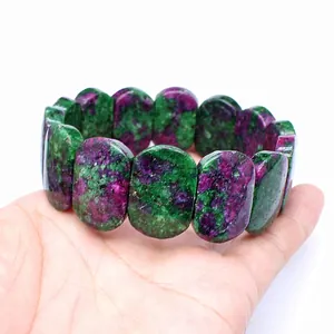 Detailed view of natural Ruby Zoisite oval stone beads bracelet shown on person's hand.