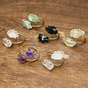 Detail showing multiple colors of raw natural stone adjustable rings on wood.