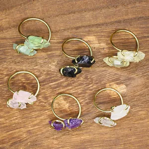 Minimalist natural raw stone rings with various colorful crystals on a rustic wooden base