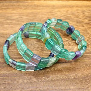Handmade natural rainbow fluorite bracelet with square gemstone beads on a wooden background