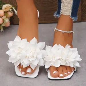 Macro view showing the intricate texture of the white fabric flower on summer slide sandals