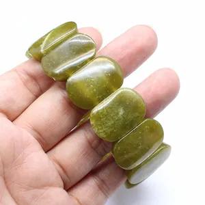 Natural green stone bracelet with polished oval beads held in hand for detail