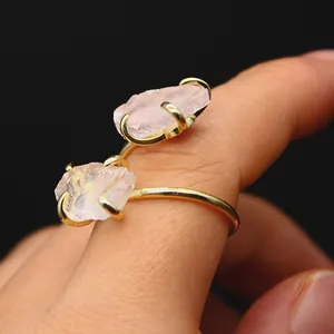 Detailed macro view of raw rose quartz stones set in a four-prong gold adjustable ring band