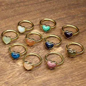 Close-up detail of various colorful heart-shaped faceted gemstone rings on a rustic wood surface