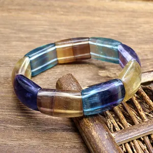 Detail view of multi-colored rectangular natural fluorite stone bead bracelet on wood