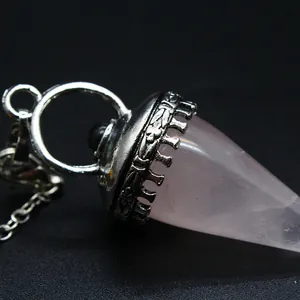 Primer plano de un péndulo de cuarzo rosa con tapa de metal plateado ornamentado