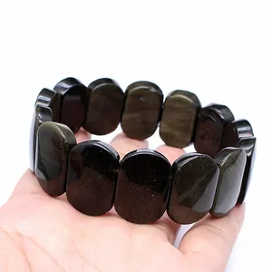 Detailed view of 11x18mm oval natural golden obsidian stone hand plate bracelet held in hand