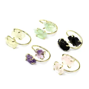 Detailed view of various natural raw stone rings with adjustable gold-tone bands.