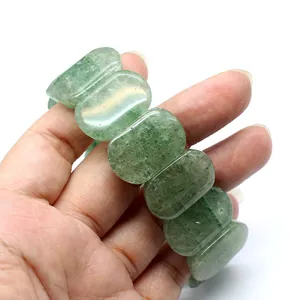 Close-up of polished green strawberry quartz bracelet segments on a hand