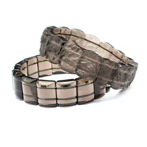Close-up detail of natural tektite and striped glass beaded bracelets on a white background