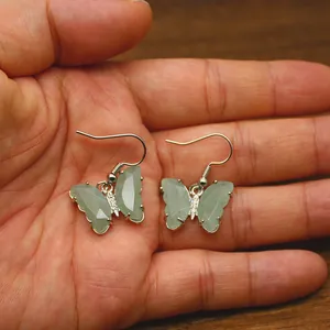 Mano che tiene orecchini a farfalla in pietra naturale con ganci argentati per donna