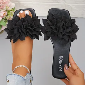 Detailed view of stylish black slide sandals featuring large 3D fabric flower decorations