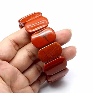 Close-up of natural red jasper stone bracelet with smooth oval beads in hand