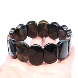 Close-up of a natural tiger's eye stone bracelet with polished oval beads held in hand