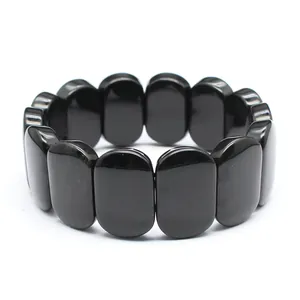 Close-up detail of smooth polished black oval natural stone beads on a stretch bracelet