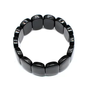 Close-up of polished black natural stone oval bead stretch bracelet on white background.