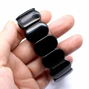 Close-up detail of a polished black oval natural stone bracelet held against white background