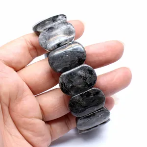 Close-up detail of a dark grey natural stone bracelet with polished 11x18mm oval beads.