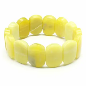 Macro detail of polished yellow oval natural stone beads on a minimalist stretch bracelet