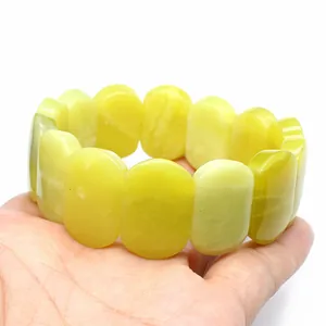 Close-up detail of a natural smooth yellow oval stone bracelet held in the palm