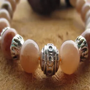 Nahaufnahme eines 8mm Sonnenstein-Perlenarmbands mit gemusterten silberfarbenen Zwischenperlen