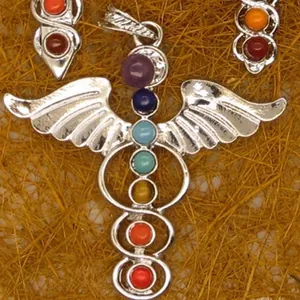 Detailed macro shot of silver caduceus pendant featuring seven colorful chakra gemstones
