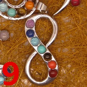 Close-up of silver infinity pendant necklace inlaid with seven colorful chakra stones.