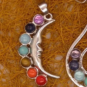 Close-up of crescent moon chakra pendant with colorful gemstones