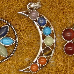 Detailed close-up view of silver-tone moon pendant featuring seven multi-color chakra gemstones