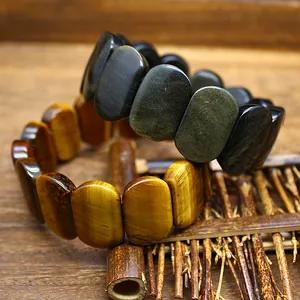 Close-up of natural tiger's eye and obsidian oval bead bracelets on a wooden base