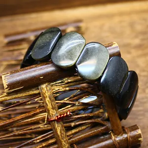 Handcrafted natural golden sheen obsidian elliptical stretch bracelet on rustic wooden stand