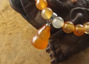 Gros plan sur un bracelet en perles d'agate orange avec un pendentif poli en gourde