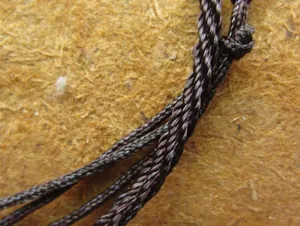 Close-up of hand-woven brown necklace cord showing intricate twisted texture