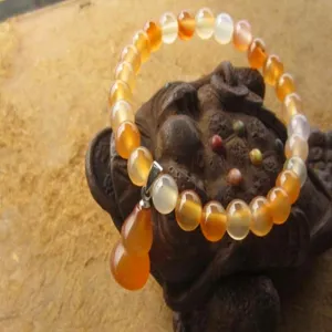 Gros plan d'un bracelet en perles d'agate cornaline avec un pendentif en forme de calebasse