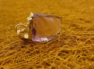 Vue rapprochée d'un pendentif en améthyste violette brute avec un bord plaqué or.