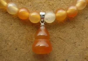 Détail en gros plan de perles d'agate cornaline orange avec un pendentif gourde
