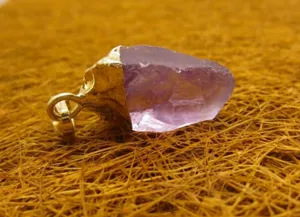 Détail macro d'un pendentif en améthyste brute avec sertissage élégant en or