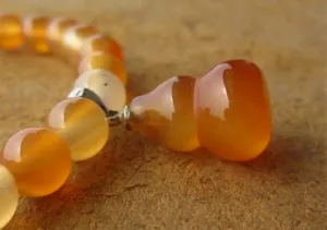 Vue macro d'un bracelet en agate cornaline orange naturelle avec pendentif calebasse