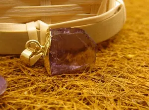 Vue détaillée d'un pendentif en améthyste violette brute du Brésil avec bord doré