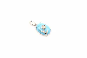 Detail shot of a blue turquoise stone pendant with silver rose floral decoration.