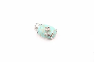 Detailed view of an oval turquoise stone pendant featuring a silver rose flower design