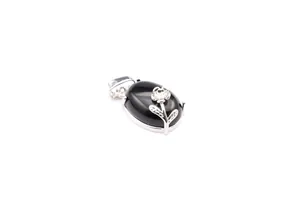 Detailed macro shot of an oval black gemstone pendant with silver floral design on white.
