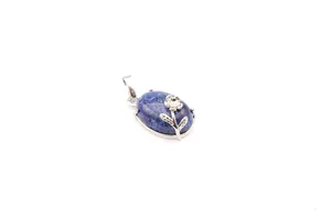 Close-up of oval blue natural stone pendant with silver flower and leaf design detail
