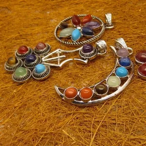 Silver chakra pendants with colorful gemstones in moon and sword shapes