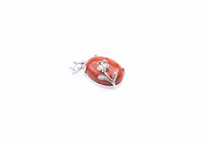 Detail view of an oval red jasper pendant with a delicate silver flower decoration on top.